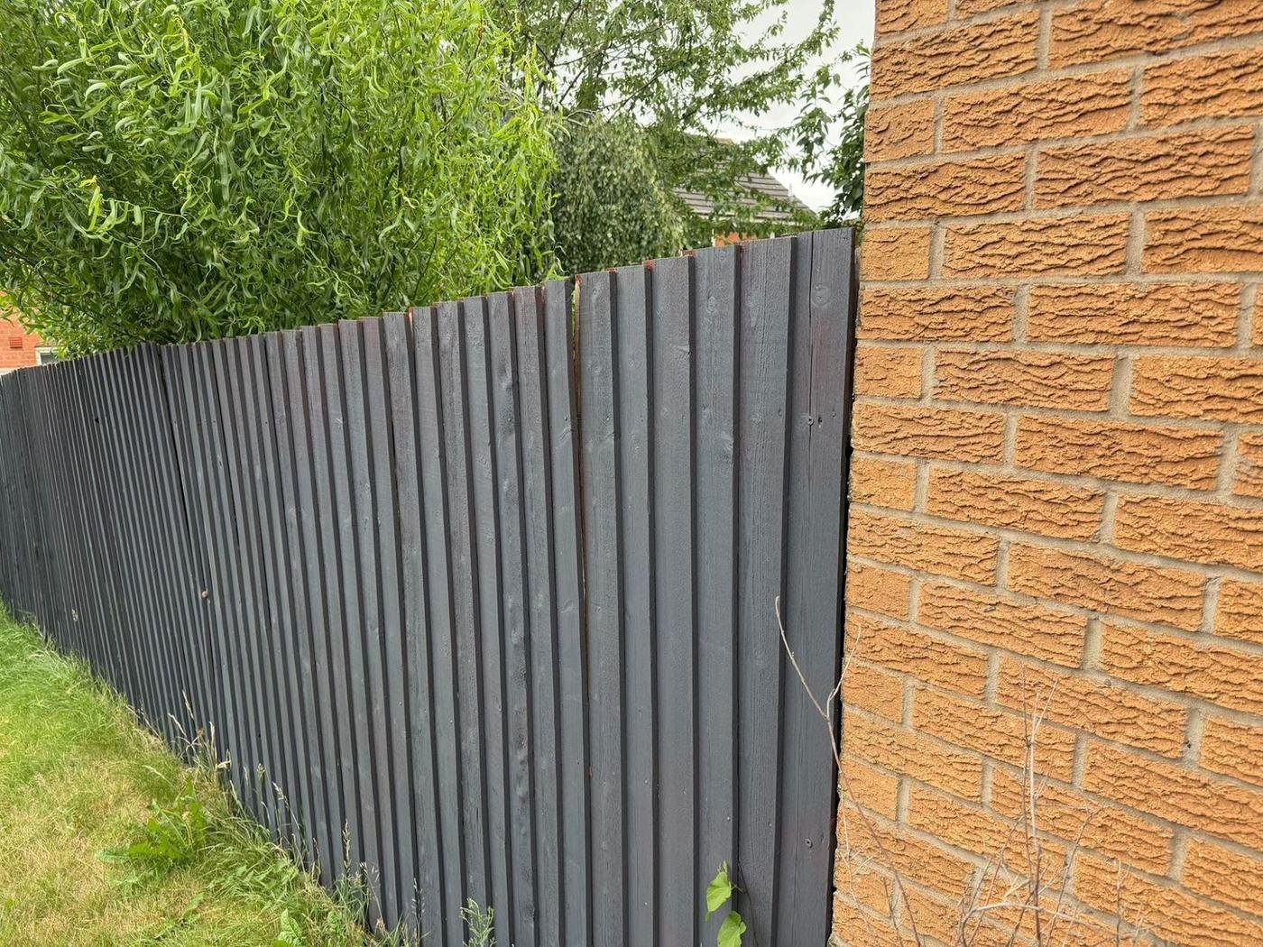 A grey fence beside a brick pillar
