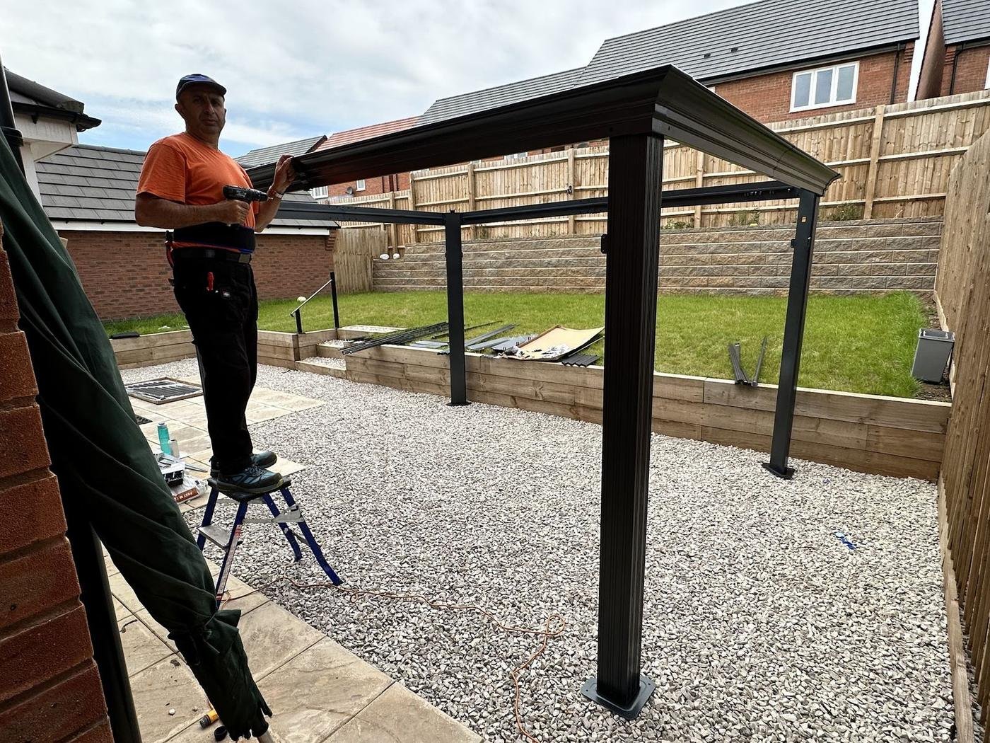 Norman putting up a pergola on a gravel patio