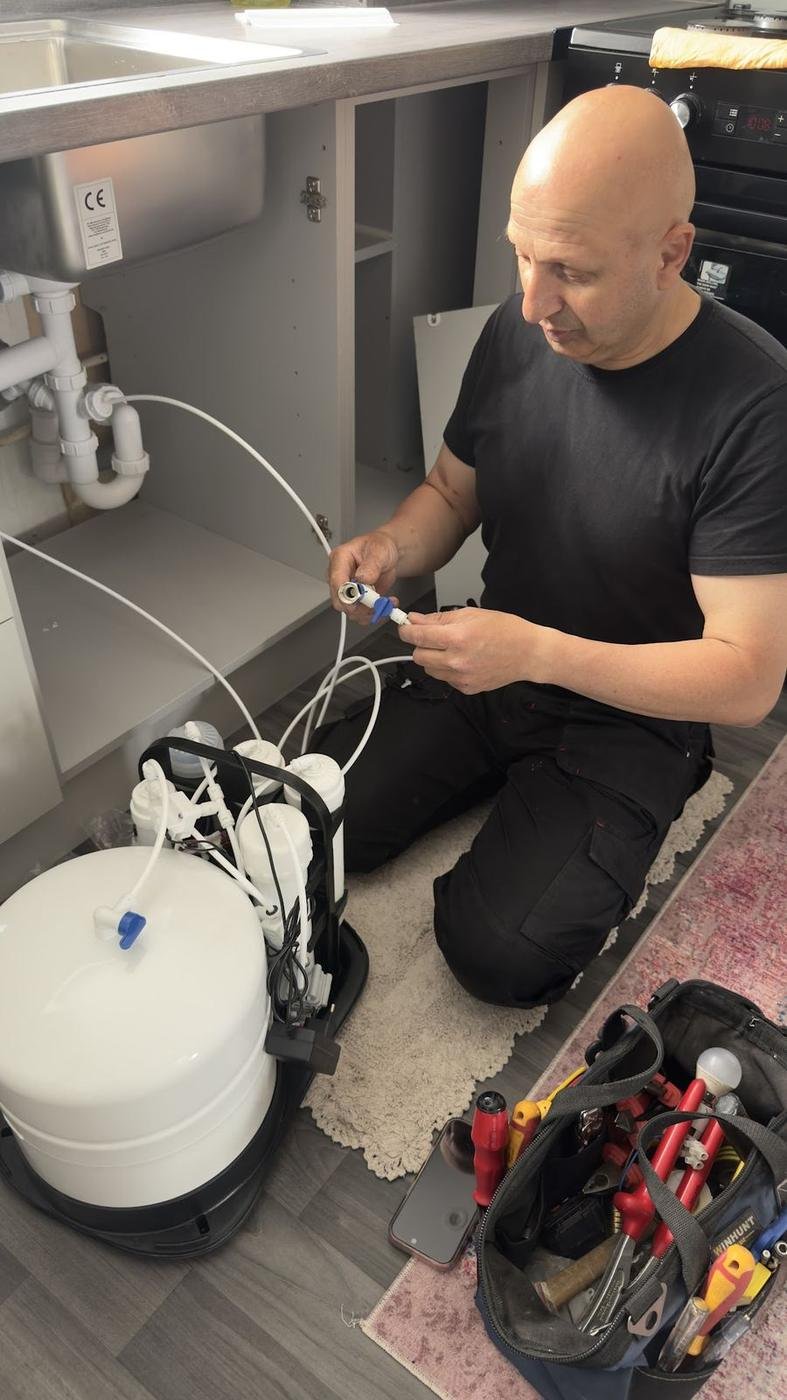 Norman fitting a water filter under a kitchen sink
